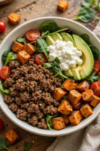 Ground beef and sweet potato bowl with seasoned beef, roasted sweet potato, avocado, greens and cottage cheese